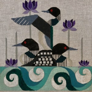 May include: A needlepoint design featuring three stylized loons with black and white markings, red eyes, and blue-gray wings. The loons are set against a light gray background with purple lotus flowers and a teal and white wave pattern at the bottom.