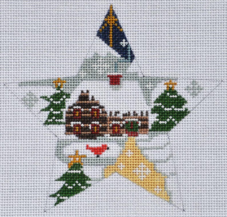 Puede incluir: Dise&ntilde;o de estrella navide&ntilde;a cosido a mano sobre lienzo. La estrella presenta una casa marr&oacute;n con detalles en rojo, &aacute;rboles de Navidad verdes y una bandera amarilla y azul. El dise&ntilde;o est&aacute; sobre un fondo gris claro.