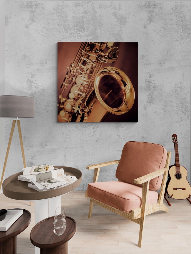 May include: A close-up of a saxophone print on canvas. The saxophone is gold-colored with intricate details, set against a dark background. The print is displayed on a gray wall, with a chair and guitar in the room.