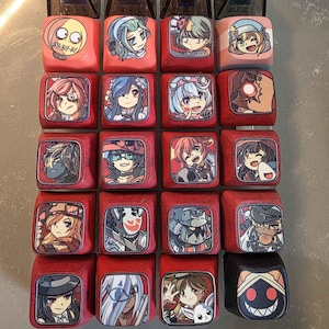 May include: A collection of twenty square mechanical keyboard keycaps arranged in a grid. Each keycap features a unique, colourful anime-style character illustration or graphic design printed on the top surface, set against a red base.