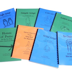 May include: A collection of nine spiral bound books with colorful covers featuring illustrations and titles related to Native American flute music. The titles include "Night Songs", "Simple Songs", "Hymns of Praise", "Native American Flute Song Book for Beginners", "Circles", "Wind Songs", "Earth Songs", and "More Simple Songs".