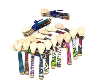 May include: A group of wooden spoons with colorful fabric wrapped around the handles. The fabric is patterned with various colors and designs.