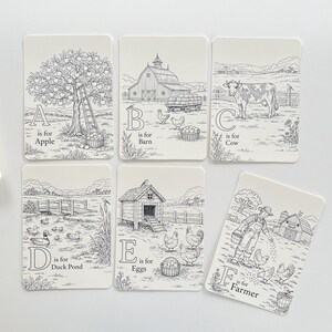 Peut inclure: Ensemble de six cartes illustr&eacute;es avec des dessins au trait noirs sur fond cr&egrave;me. Chaque carte pr&eacute;sente une lettre de l'alphabet et une image sur le th&egrave;me de la ferme, comme un pommier, une grange, une vache, un &eacute;tang aux canards, des &oelig;ufs et un fermier.