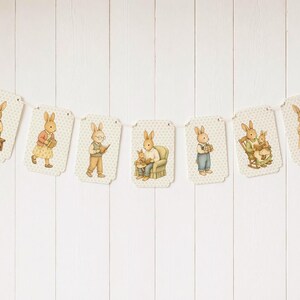May include: A banner featuring illustrated bunnies in various poses, each on a tag with a dotted background. The bunnies are depicted reading, carrying baskets, and sitting in chairs. The banner is strung on a white string.