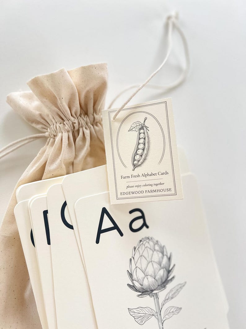 May include: A set of Farm Fresh Alphabet Cards with a drawstring bag. The cards feature black uppercase and lowercase letters, and botanical illustrations. The tag reads "Farm Fresh Alphabet Cards" and "Edgewood Farmhouse".