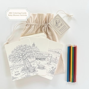 Peut inclure: Un ensemble de cartes de coloriage ABC avec des illustrations sur le th&egrave;me de la ferme, dont un pommier et une grange, avec le texte "ABC Coloring Cards Baby Shower Activity". Les cartes sont dans un sac en tissu beige avec des crayons de couleur.