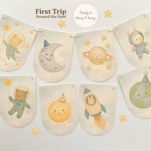 May include: A banner with space-themed illustrations, including a moon, sun, planet, rocket, and animals in astronaut suits. The banner has the text "First Trip Around the Sun!" and "Ready to string & hang."