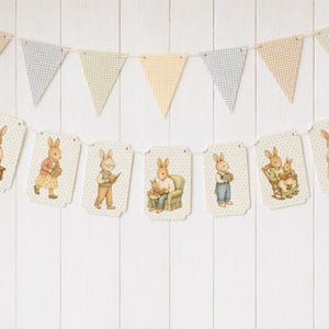 May include: A decorative banner featuring illustrated bunnies in various poses, strung with a matching gingham pennant garland. The bunny illustrations depict scenes of reading, holding gifts, and family moments, all set against a white background.