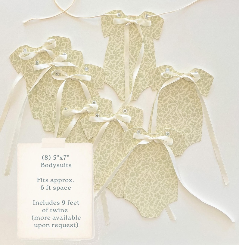 May include: A garland of eight paper bodysuits, each measuring 5" x 7", with a cream-colored fern pattern. Each bodysuit has a cream ribbon bow and is strung on twine. The garland is suitable for a 6 ft space.
