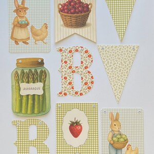 May include: A collection of decorative banners and letter cutouts with a farm theme. The banners feature illustrations of cherries, a strawberry, and a bunny with eggs. The letters are decorated with floral and gingham patterns.
