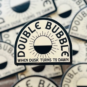 May include: Multiple black and white stickers with the text "Double Bubble" and the phrase "When Dusk Turns to Dawn".