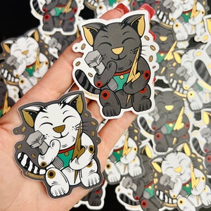 May include: A set of black and white lucky cat stickers with a gold lightning bolt and wrench. The stickers have the text "Livingrove" on them.