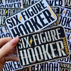 May include: Two rectangular embroidered patches featuring the text SIX FIGURE HOOKER in bold lettering with a yellow lightning bolt icon between the words. One patch has black text on a white background, and the other has white text on a black background.