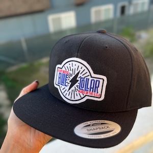 May include: Black and white baseball cap with a blue, red, and white patch that says "Rare Breed Blue Collar Made in the U.S.A." The cap has a black and silver "The Authentic Yupoong Snapback Yupoong Since 1974" label on the back.