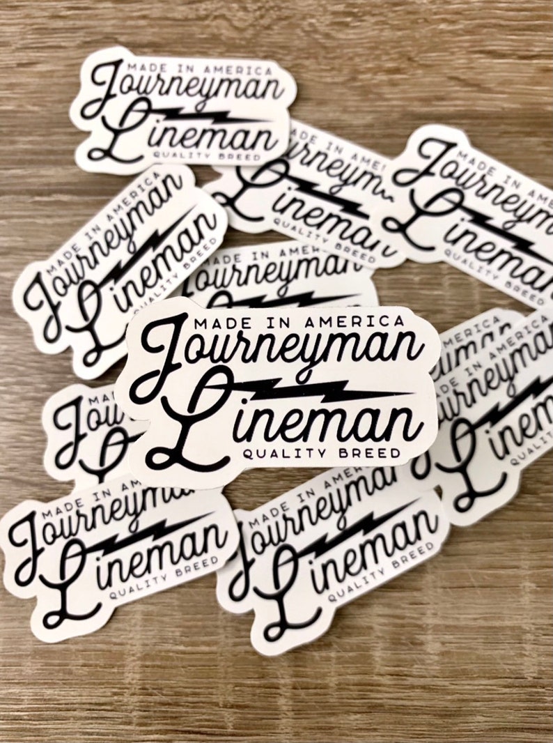 May include: A collection of white stickers with black text and a lightning bolt graphic. The text on the stickers reads "Made in America Journeyman Lineman Quality Breed".