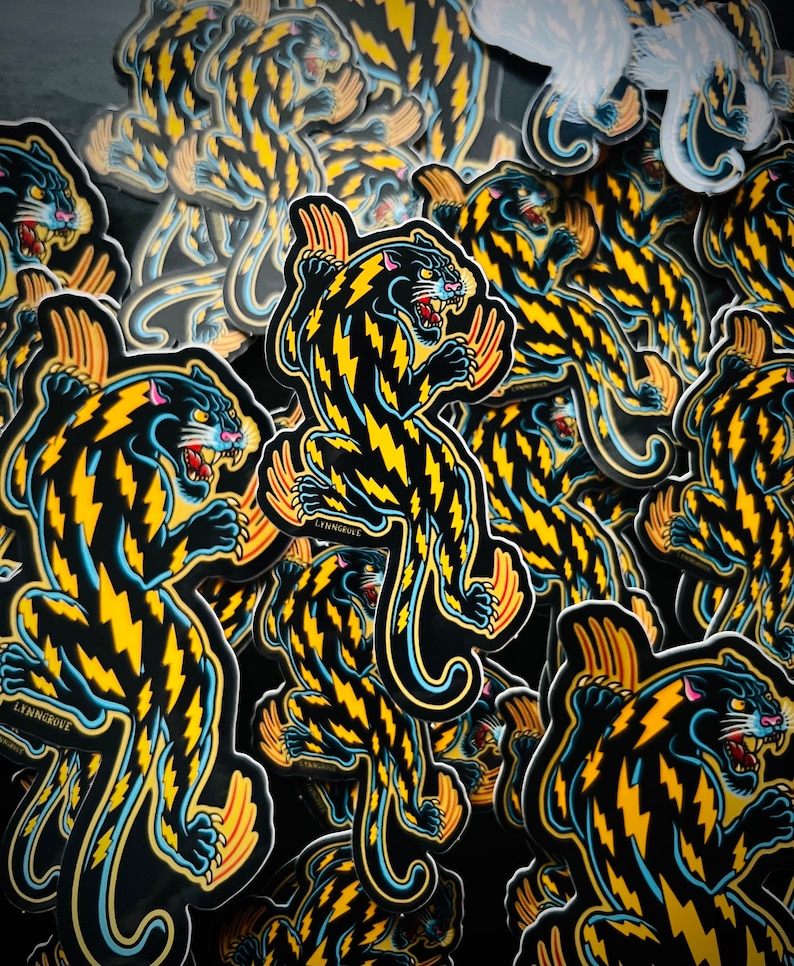 May include: A stack of black and yellow panther stickers with lightning bolt patterns. The stickers have a blue outline and the text "LYINGROVE" is visible on some of the stickers.