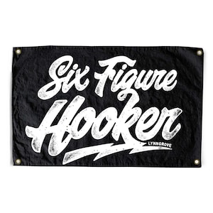 May include: Black banner with white text that reads "Six Figure Hooker" in a bold, stylized font. The banner has grommets in each corner for hanging. The word "LYNNGROVE" is printed below the text.