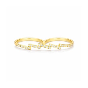 May include: A gold double-finger ring with a zig-zag pattern. The ring is embellished with small, clear, sparkling stones. The ring is set against a white background.