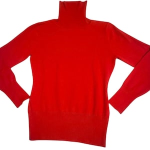 May include: A bright red turtleneck sweater. The long-sleeved sweater has a ribbed hem and cuffs. The turtleneck is folded over. The sweater is made of a soft material.