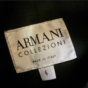 May include: White tag with black text that reads "ARMANI COLLEZIONI" and "MADE IN ITALY". The tag also has a smaller white tag with the number "6" on it.