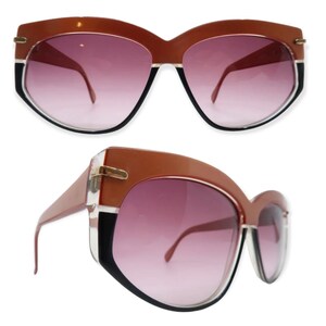 May include: A pair of brown and black sunglasses with a gradient lens. The sunglasses have a unique, angular shape.