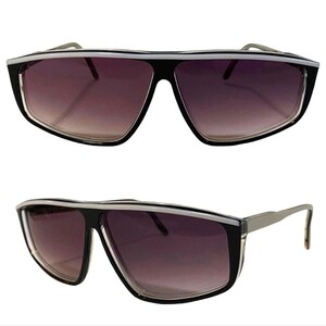 May include: Black sunglasses with a white stripe across the top of the frame. The lenses are a dark gradient color.