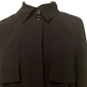 May include: A black long-sleeved collared jacket with a button closure. The jacket has a simple design and a slightly fitted silhouette.