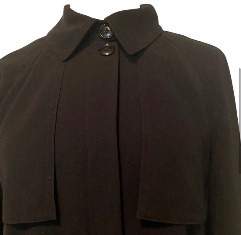 May include: A black long-sleeved collared jacket with a button closure. The jacket has a simple design and a slightly fitted silhouette.