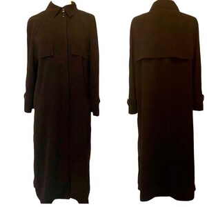 May include: A long, black trench coat with a button-up front and a collar. The coat has a belt and pockets.