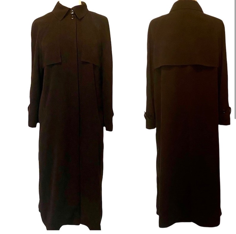May include: A long, black trench coat with a button-up front and a collar. The coat has a belt and pockets.