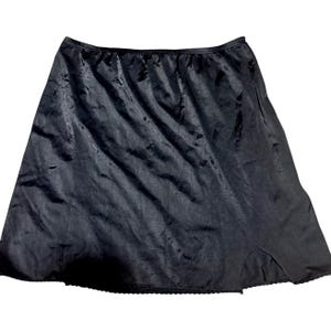 May include: A black satin slip skirt with a scalloped lace hem. The skirt has a slight A-line shape and a slit on the side. The fabric has a subtle sheen.