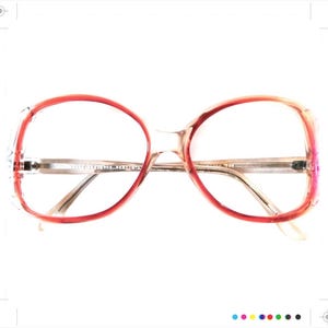 May include: A pair of red and clear plastic oval-shaped eyeglasses with a gold metal bridge.