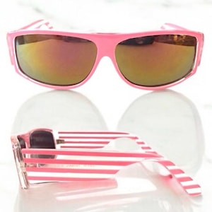 Könnte beinhalten: Rosa gestreifte Sonnenbrille mit verspiegelten Gläsern. Die Sonnenbrille ist zusammengeklappt und die Gläser zeigen zur Kamera.