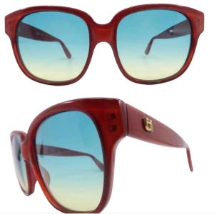May include: Red plastic sunglasses with blue gradient lenses. The sunglasses have a gold logo on the side.