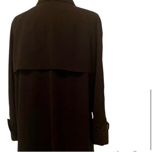 May include: A long-sleeved, dark brown trench coat with a buttoned closure and a single button on each cuff.