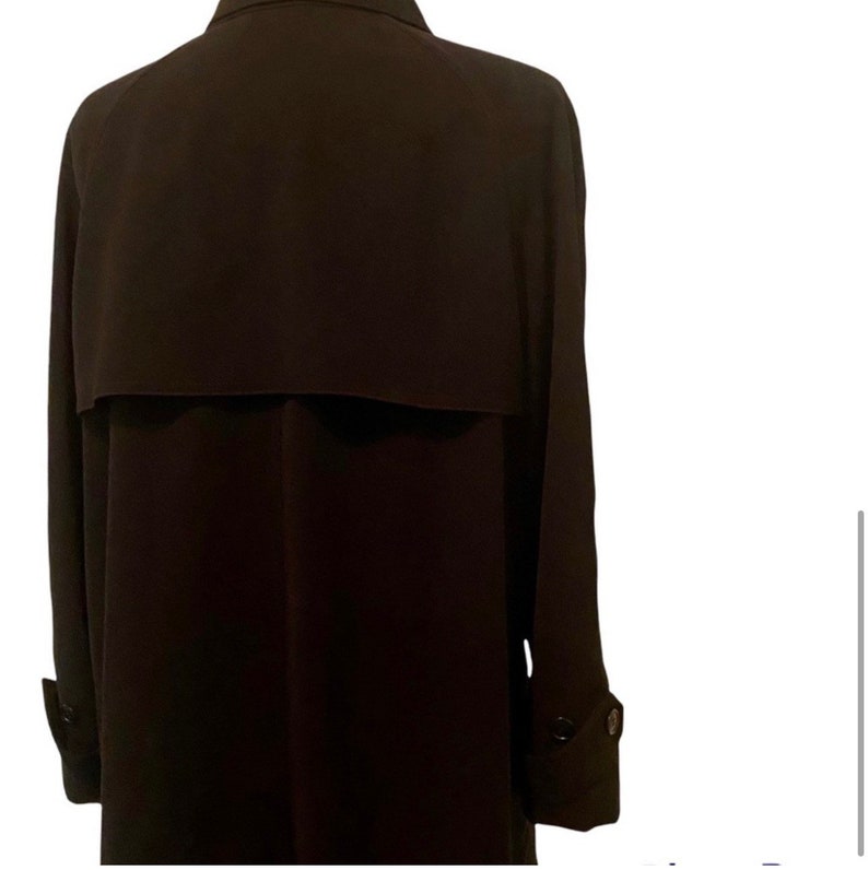 May include: A long-sleeved, dark brown trench coat with a buttoned closure and a single button on each cuff.