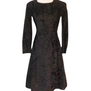 May include: A black, long-sleeved dress with a round neckline and a flared skirt. The dress appears to be made of a soft, textured fabric, and it has a fitted bodice. The dress is a solid color and suitable for various occasions.