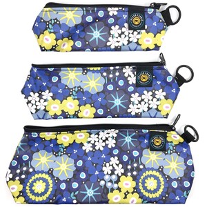 May include: Three zippered pouches with a floral print in shades of blue, yellow, white, and black. The pouches have a black zipper and a black strap with a metal ring.