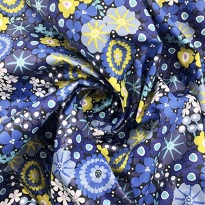 May include: Blue fabric with a repeating pattern of yellow and blue flowers. The fabric is folded and the pattern is visible on both sides.
