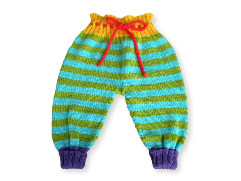 May include: Striped knitted baby pants with a yellow, green, and blue color scheme. The pants have a red drawstring and purple cuffs.