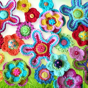 May include: A collection of colorful crocheted flowers in various shapes and sizes. The flowers are made with different colored yarns and have a variety of button embellishments in the center.