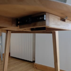 Puede incluir: Una mesa de madera con un caj&oacute;n oculto que se desliza sobre rieles met&aacute;licos. El caj&oacute;n est&aacute; hecho del mismo tipo de madera que la mesa y est&aacute; parcialmente abierto.