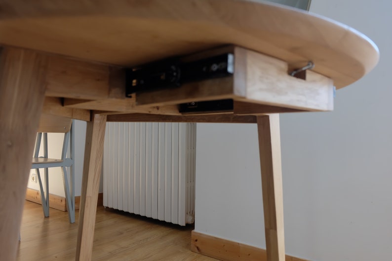 Puede incluir: Una mesa de madera con un caj&oacute;n oculto que se desliza sobre rieles met&aacute;licos. El caj&oacute;n est&aacute; hecho del mismo tipo de madera que la mesa y est&aacute; parcialmente abierto.