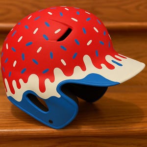 Pode incluir: Capacete de beisebol vermelho com um design de granulado branco, azul e vermelho. O capacete tem um design de gotejamento de glacê branco ao longo da aba e uma proteção de queixo azul.