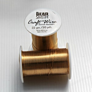 May include: A spool of gold-colored craft wire labeled "The Bead Smith Craft Wire Tarnish Resistant 22 ga./20 yds. Not for electrical use. Made in the USA."