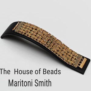 May include: A gold beaded bracelet with iridescent beads on a black display stand. The House of Beads Maritoni Smith is written below the stand.
