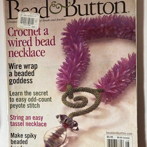 Puede incluir: Portada de la revista Bead & Button con un collar de cuentas de color morado y verde. El texto de la portada dice "Tejer un collar de cuentas con alambre".