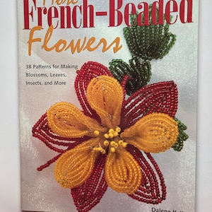 Puede incluir: Portada de libro con el título "More French-Beaded Flowers" y un primer plano de una flor de cuentas con cuentas rojas, amarillas y verdes. La portada del libro también incluye el texto "38 Patterns for Making Blossoms, Leaves, Insects, and More" y el nombre del autor, "Dalene Kelly".