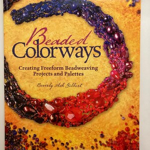 Puede incluir: Un libro titulado "Beaded Colorways: Creating Freeform Beadweaving Projects and Palettes" de Beverly Ash Gilbert. La portada presenta un collar de cuentas de colores en tonos de morado, rojo y marrón. El libro incluye ruedas de colores personalizadas.