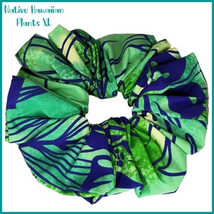 May include: A green and blue patterned scrunchie with a large, gathered design. The scrunchie has a floral pattern with a white background.